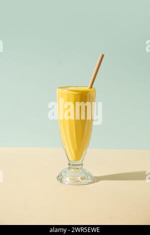Mango tropicale, lassi di frutta della passione, frullato in tradizionale vetro alto con paglia di bambù su sfondo retro, giallo e blu vintage. Healt Foto Stock