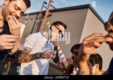 allegri amici interrazziali con eleganti occhiali da sole che bevono tequila con lime e sale alla festa Foto Stock