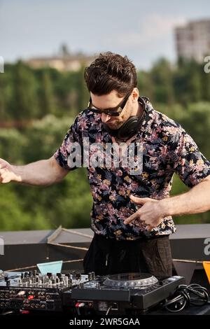 Un uomo allegro dall'aspetto vivace con occhiali da sole che suonano musica come DJ alla festa sul tetto Foto Stock