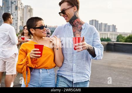 jolly uomo e donna con coppe rosse che si guardano l'un l'altro con i loro diversi amici sullo sfondo Foto Stock