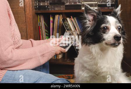 Senior che guarda le cassette con il suo cane da compagnia. Foto Stock