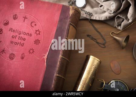 Dettaglio del vecchio libro sullo studio delle religioni nel mondo tavolo in legno con oggetti decorativi. Vista dall'alto. Foto Stock