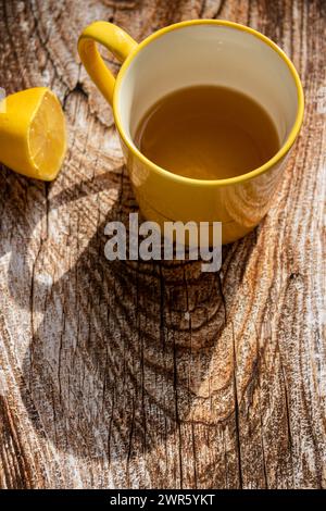 Teiera (pressa francese) con mezzo limone e teiera al tavolo di legno sul balcone, tè mattutino, aromaterapia aromatica fresca ed erboristica, tè biologico Foto Stock