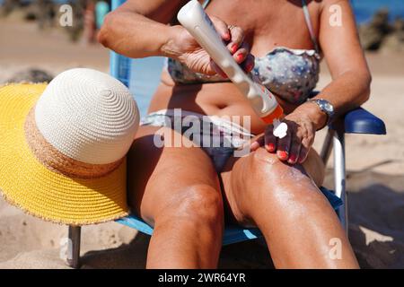 donna irriconoscibile che prende il sole e applica crema solare nel suo corpo. cura della pelle per la prevenzione del cancro della pelle Foto Stock