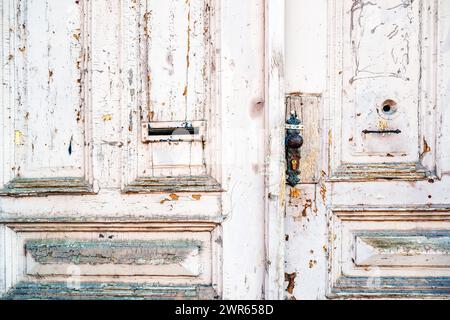 Vecchia porta di legno. La vernice bianca con agenti atmosferici è sfaldatura e sbucciatura della superficie. Trama e sfondo grintosi. Foto Stock