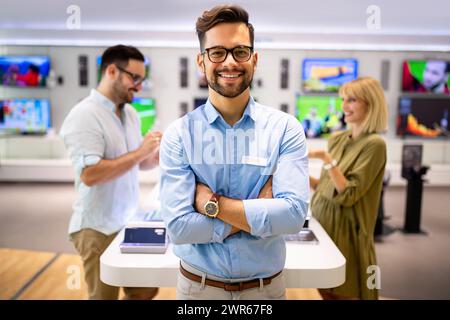 Il consulente di vendita consiglia le persone che scelgono nuovi dispositivi digitali nei punti vendita. Consulenza professionale Foto Stock