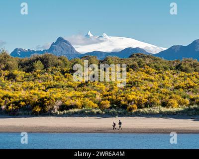 I turisti camminano sulla spiaggia di Raul Marin Balmaceda, il vulcano innevato Corcovado sul retro, Patagonia, Cile Foto Stock