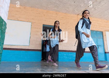 Gruppo di bambini rurali indiani in uniforme scolastica che corrono in corridoio scolastico. Concetto educativo Foto Stock