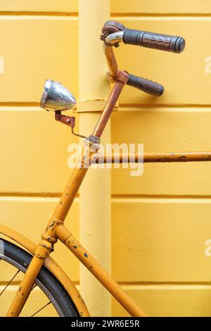 Primo piano di una bici gialla contro una parete gialla corrispondente Foto Stock