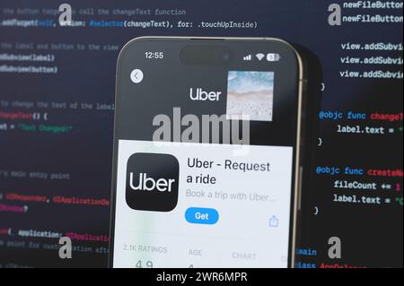 New York, USA - 23 febbraio 2024: Uber su schermo iphone in background di programmazione codice sfocato Foto Stock