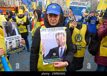 Bucarest, Romania. 11 marzo 2024. Operatori sanitari, con manifesti con i ritratti del primo ministro Marcel Ciolacu e del ministro della salute Alexandru Rafila, unionista della Federazione rumena di solidarietà sanitaria, protesta davanti alla sede del governo rumeno insoddisfatto degli aumenti salariali ricevuti annunciando che, se le loro richieste non sono soddisfatte, potrebbe essere l'ultima manifestazione fino allo sciopero generale. Lucian Alecu/Alamy Live News Foto Stock