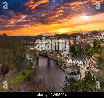 Un paesino inglese panoramico al tramonto, caratterizzato da un fiume e un ponte Foto Stock