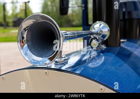 Primo piano del clacson vintage in acciaio su un'auto blu nel parco, attenzione selettiva Foto Stock