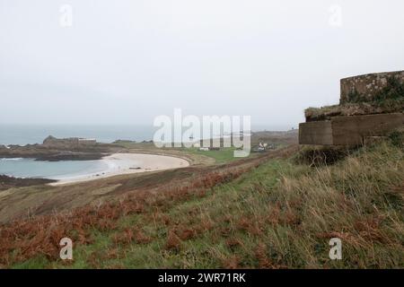 Occupazione tedesca nazista il palo di cemento della mitragliatrice si affaccia sulla spiaggia sabbiosa di Saye, le Isole del Canale di Alderney, il canale inglese nebbioso giorno Foto Stock