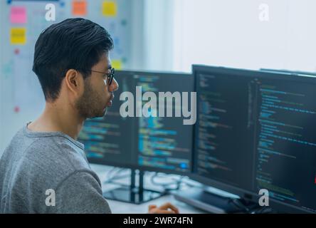 I tecnici asiatici sviluppano un'applicazione di codifica con dati software posizionati davanti al monitor del computer in ufficio Foto Stock