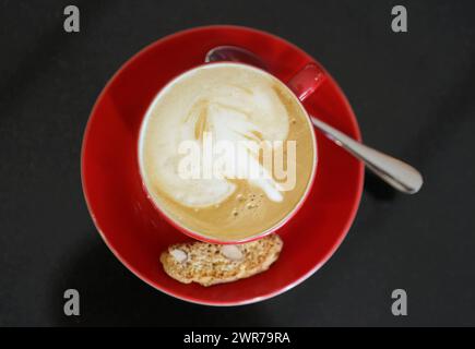 Symbolbild zum Thema Kaffee Hier: Rote Kaffeetasse mit Cappucino *** immagine simbolica sul tema del caffè qui tazza di caffè rosso con cappuccino Foto Stock