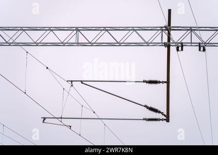 Linee elettriche aeree contro un cielo nuvoloso per l'alimentazione ferroviaria Foto Stock