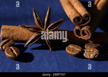 Chicchi di caffè, anice stellato e spezie alla cannella su sfondo blu intenso Foto Stock