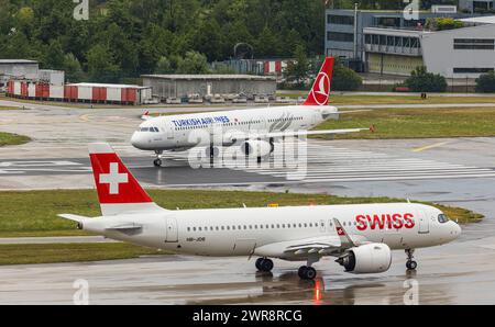 Ein Airbus A321-200 von Turkish Airlines startet von piste 28 auf dem Flughafen Zürich. Registrazione TC-JSC. Davor wartet ein Airbus A220-100 von SWIs Foto Stock