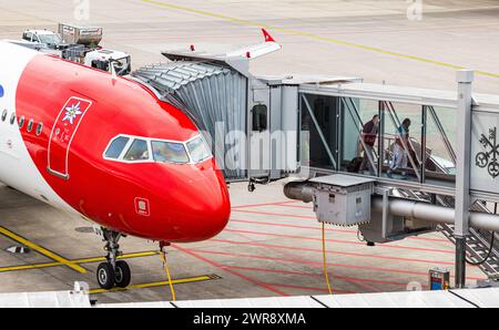 Flugpassagiere steigen aus dem Airbus A320-214 von Edelweiss Air aus. DAS Flugzeug ist nach der Landung an einem Fingerdok des Terminal B geparkt. Reg Foto Stock