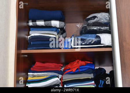 Attraverso la porta aperta dell'armadio, si possono vedere vestiti distesi sugli scaffali. Foto Stock