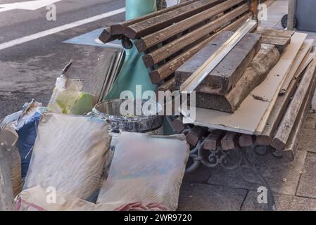 Un mucchio di materiali da costruzione su un banco in metallo e spranghe in legno nel mezzo della strada Foto Stock