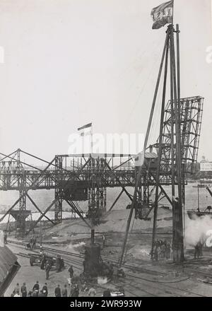 La posa del primo palo per la nuova costruzione della linea Holland-America nel porto di Rotterdam. I lavori di restauro, dopo le numerose distruzioni durante gli anni di occupazione, sono in pieno svolgimento nel porto di Rotterdam. Sulla banchina, i lavoratori sono impegnati a guidare il primo palo per i nuovi edifici del vecchio sito distrutto della linea Holland-America., van 't Hof, Anefo, Rotterdam, ottobre 1945, supporto fotografico, larghezza 16,5 cm x altezza 23,5 cm, fotografie documentarie Foto Stock