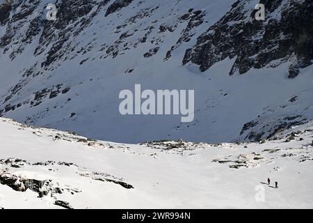 Due escursionisti attraversano il paesaggio innevato di montagna vicino a Velické pleso a Velická dolina, sopra Tatranská Polianka, alti Tatra Foto Stock