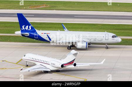 VOR einem Bombardier Global 6500 von NETJETS Europe mit der Registration CS-gli rollt ein Airbus A320-251N von SAS Scandinavian Airlines mit der Regis Foto Stock