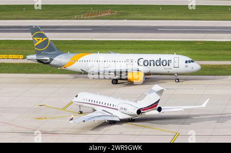 VOR einem Bombardier Global 6500 von NETJETS mit der Registration CS-gli rollt ein Airbus A320-214 von Condor mit der Registration D-AICS auf dem Flug Foto Stock