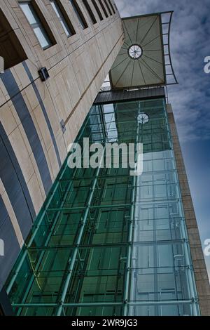 Dettagli architettonici moderni con facciata in vetro e torre dell'orologio su un cielo blu a Leeds, Regno Unito. Foto Stock