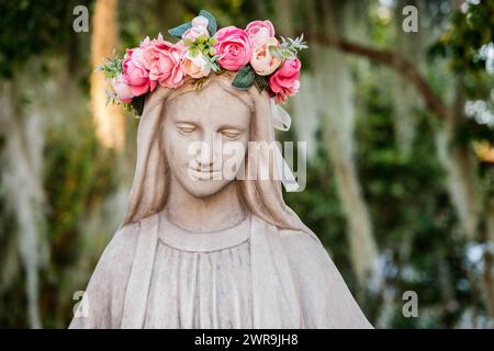 Statua della Vergine Maria con una corona di fiori rosa sulla testa Foto Stock