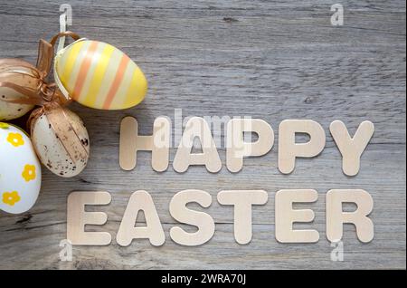 Buona Pasqua testo su sfondo in legno con uova di Pasqua decorative Foto Stock