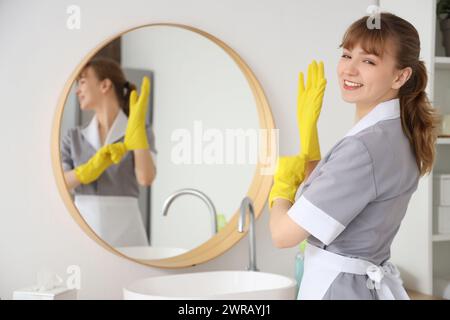 Giovane cameriera con guanti di gomma in bagno Foto Stock