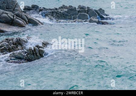 Onde schiumose che si tuffano contro una formazione rocciosa costiera, in Corea del Sud Foto Stock
