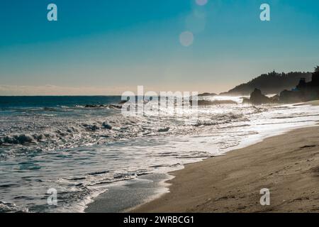 Un paesaggio marino accidentato con onde sotto il sole del mattino che si infrangono sulla spiaggia e rocce sotto un bellissimo cielo blu, in Corea del Sud Foto Stock