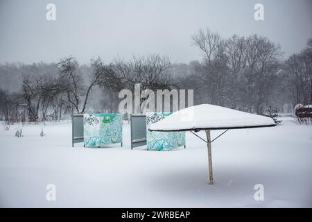 Spiaggia con ombrellone e cabine durante le forti nevicate invernali Foto Stock