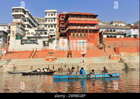 Persone su barche a ghat di fronte a edifici tradizionali in un paesaggio urbano, Varanasi, Uttar Pradesh, India Foto Stock