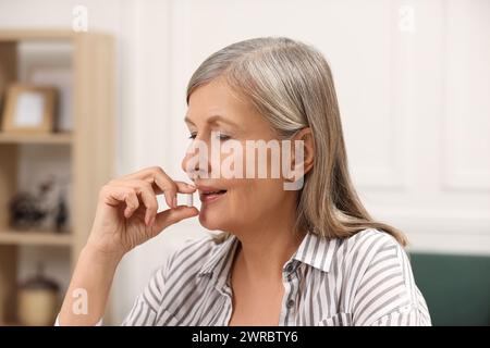 Menopausa, terapia ormonale sostitutiva. Donna che prende pillole a casa Foto Stock