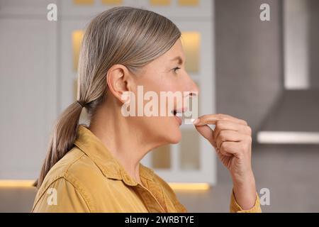 Menopausa, terapia ormonale sostitutiva. Donna che prende pillole in cucina Foto Stock