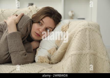 Giovane donna triste sdraiata sul divano di casa, spazio per il testo Foto Stock