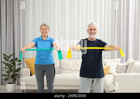 Coppia senior che fa esercizio fisico con fasce elastiche fitness a casa Foto Stock