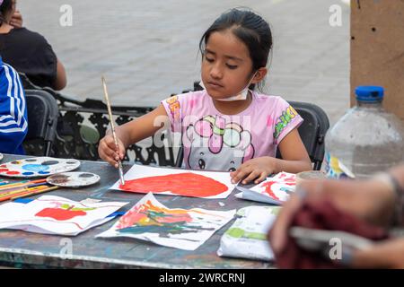 Oaxaca, Messico - studenti che dipingono in un corso d'arte temporaneo nello zocalo. Una ragazza dipinge un cuore il giorno prima di San Valentino. Foto Stock