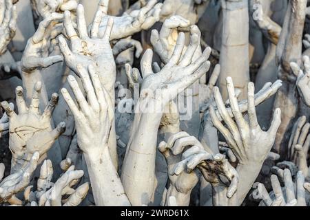 Chiang Rai, Thailandia - dicembre 2022: Mani famose dall'arte infernale sul territorio del Tempio bianco Wat Rong Khun molte statue Foto Stock