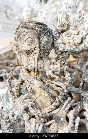 Chiang Rai, Tailandia - dicembre 2022: Le famose teste urlanti si riversano dall'arte infernale sul territorio del Tempio bianco Wat Rong Khun molte statue Foto Stock