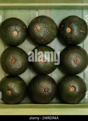 Un mucchio di avocado sono impilati uno sopra l'altro su Una superficie verde Foto Stock