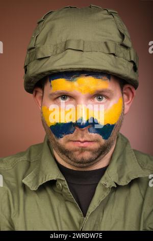 Uomo che esprime rispetto per l’Ucraina con colori nazionali sul viso Foto Stock