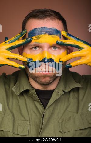 Uomo che esprime rispetto per l’Ucraina con colori nazionali sul viso Foto Stock