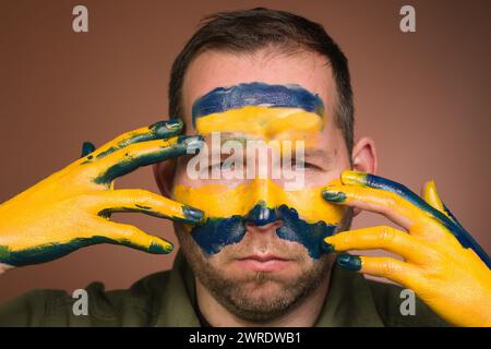 Uomo che esprime rispetto per l’Ucraina con colori nazionali sul viso Foto Stock