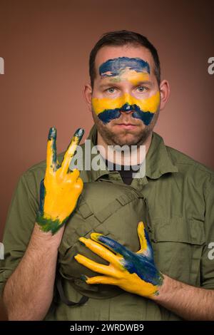 Uomo che esprime rispetto per l’Ucraina con colori nazionali sul viso Foto Stock